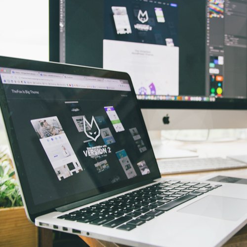 Laptop computer displaying an e-commerce website design interface in a workspace.