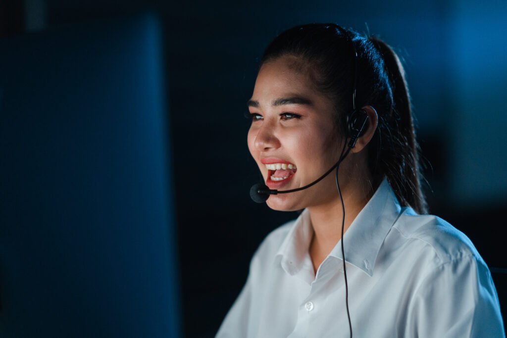 Customer service representative smiling while wearing a headset.