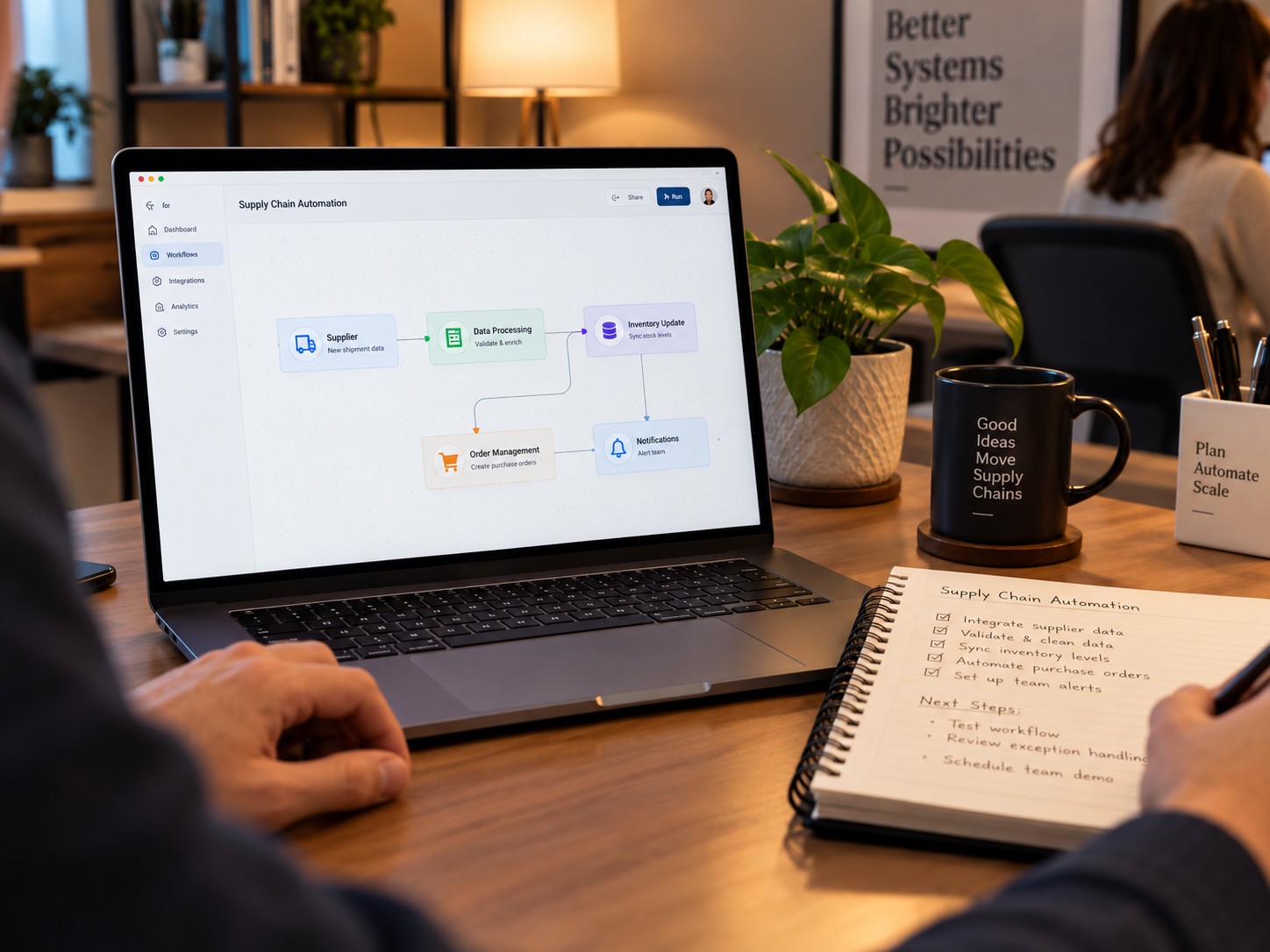 Laptop screen showing a supply chain automation flowchart next to a coffee mug and handwritten notes on a office desk.